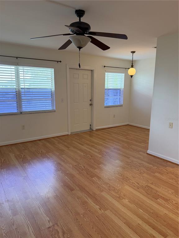 A living room features light wood-look flooring, a ceiling fan, and two windows with blinds — 5850 18TH STREET N UNIT 16, ST PETERSBURG, FL