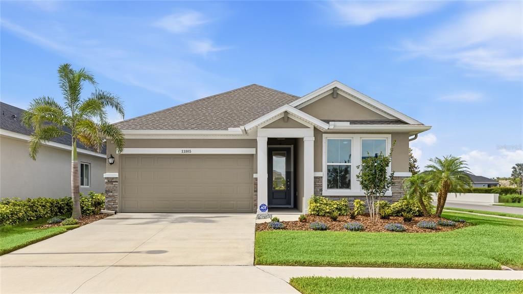 A single-story suburban house with a beige exterior, a two-car garage, and a landscaped yard — 11805 CATAWBA COVE, PARRISH, FL