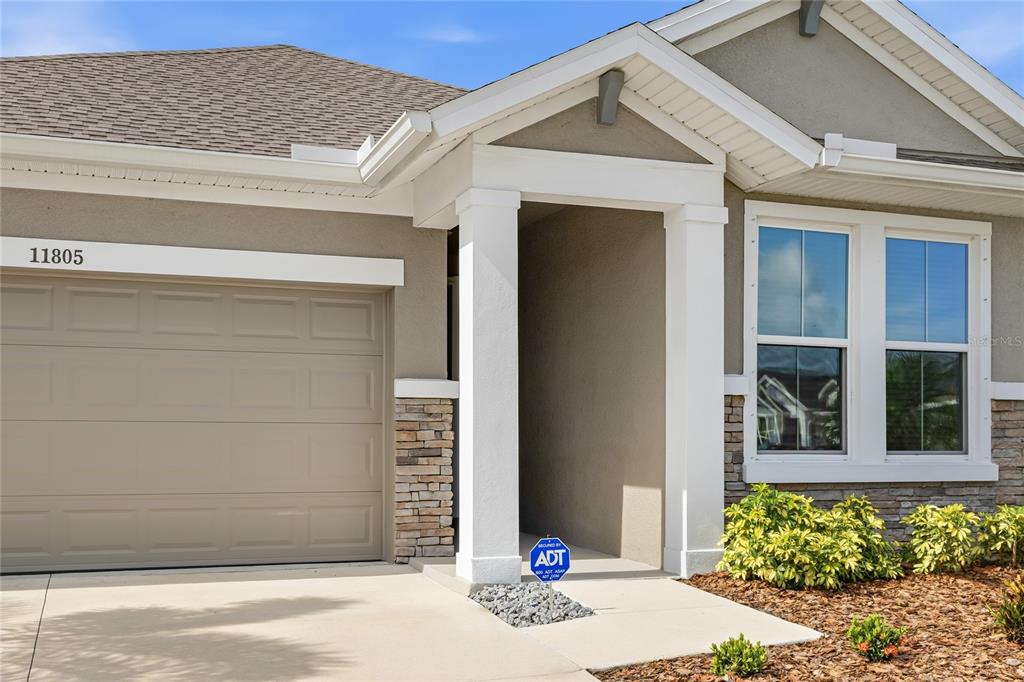 The exterior of a single-story house features a garage, a covered entryway, and stone accents — 11805 CATAWBA COVE, PARRISH, FL