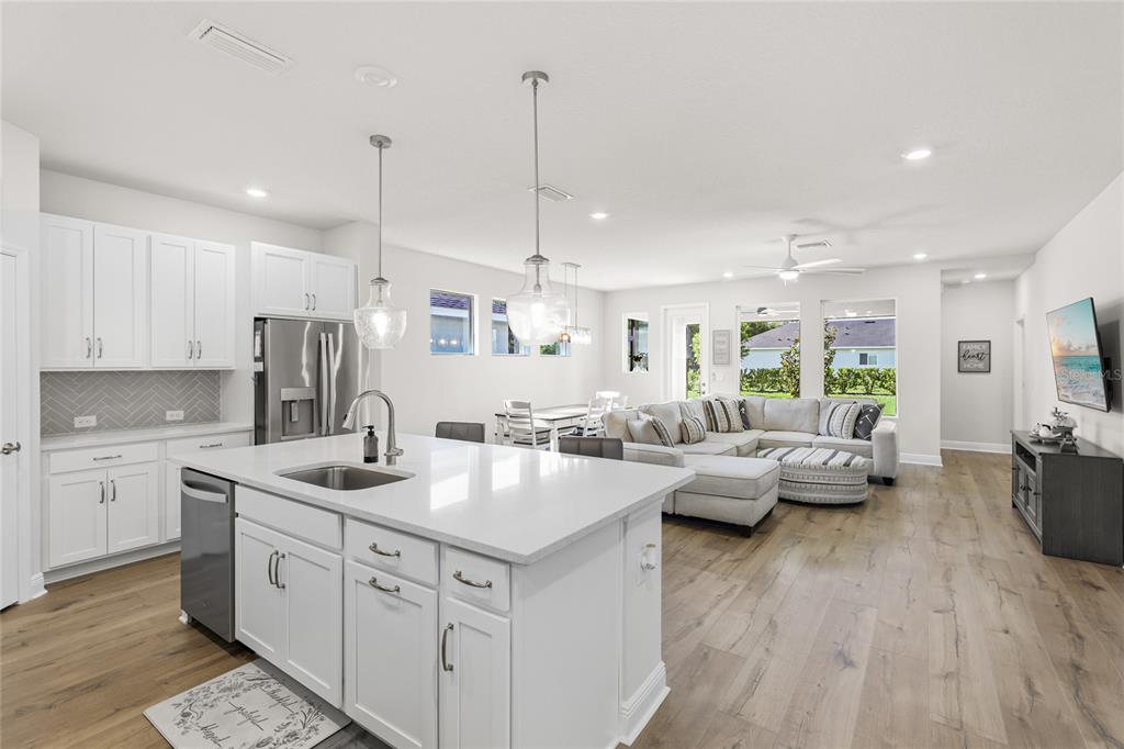 A bright open-concept kitchen and living area with white cabinets, a large island, and flooring — 11805 CATAWBA COVE, PARRISH, FL