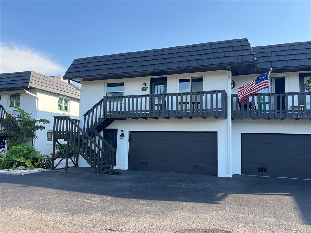 A two-story townhouse exterior features a dark garage door, an upper balcony, and wooden stairs — 10313 WATERBIRD WAY, BRADENTON, FL