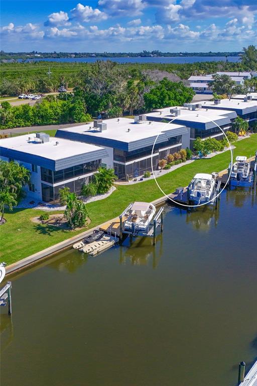 An aerial view shows multi-story waterfront condominiums with private boat slips along a canal — 10313 WATERBIRD WAY, BRADENTON, FL