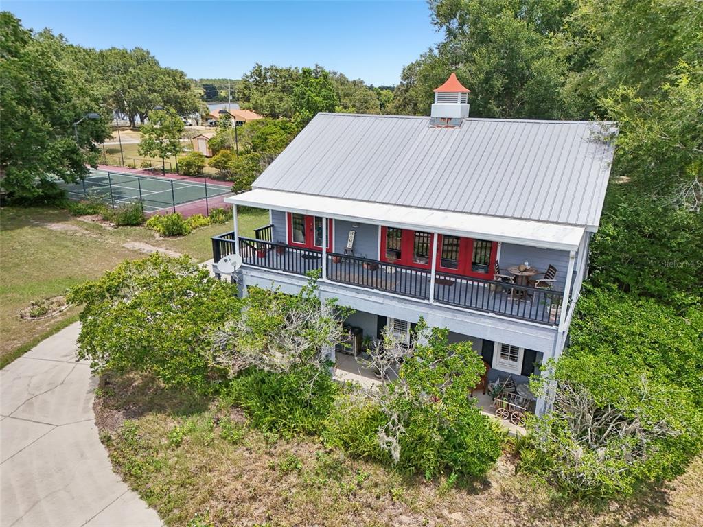 An elevated two-story house with a metal roof, red doors, and a wrap-around balcony — 18249 ROSE STREET, GROVELAND, FL