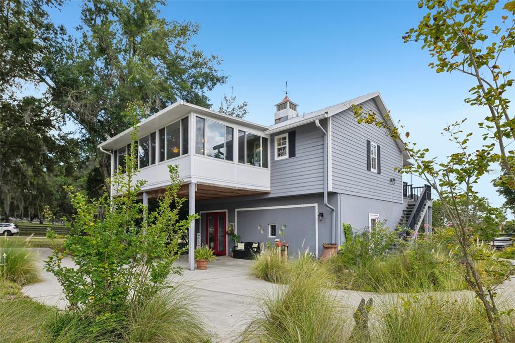 A tennis court with a green surface and red borders surrounded by trees and fencing — 18249 ROSE STREET, GROVELAND, FL