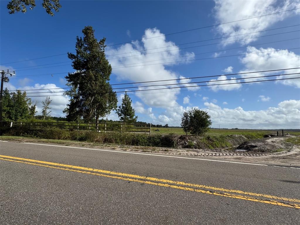 A paved road runs alongside a grassy field with trees and a wooden fence — 380 CR 13 S STREET, ST AUGUSTINE, FL