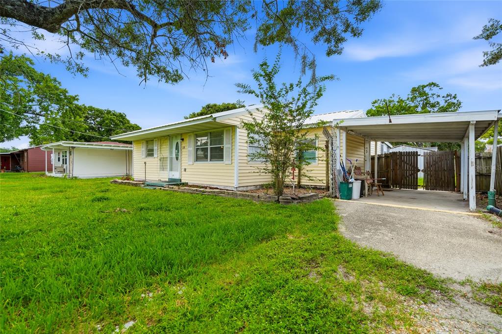 A yellow single-story house features a front porch, a carport, and a grassy yard — 128 NW 10TH DRIVE, MULBERRY, FL