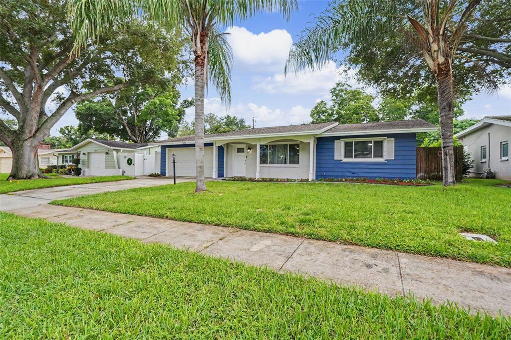 A single-story house with blue siding, a white garage, and palm trees in the front yard — 1340 WILLIAMS DRIVE, CLEARWATER, FL