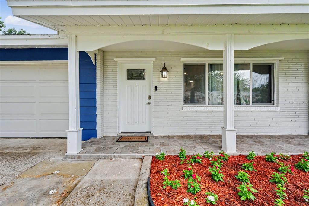 A white brick house exterior features a front porch, a white door, and red mulch — 1340 WILLIAMS DRIVE, CLEARWATER, FL