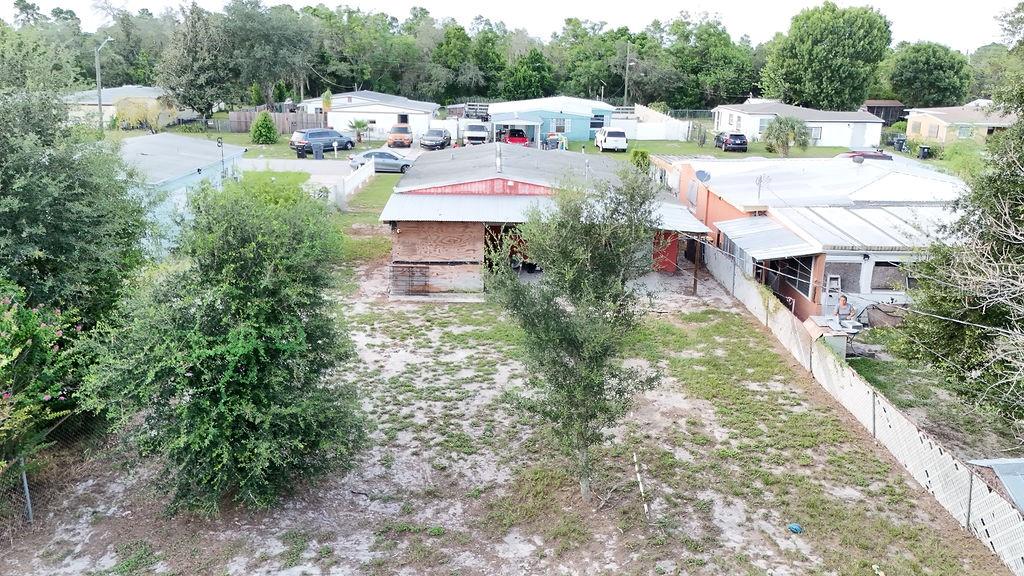 An aerial view shows a residential backyard with a red-roofed house and a fenced lot — 99 YALE AVENUE, FROSTPROOF, FL