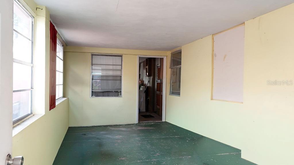 A sunroom with pale yellow walls, a green painted floor, and multiple windows — 99 YALE AVENUE, FROSTPROOF, FL