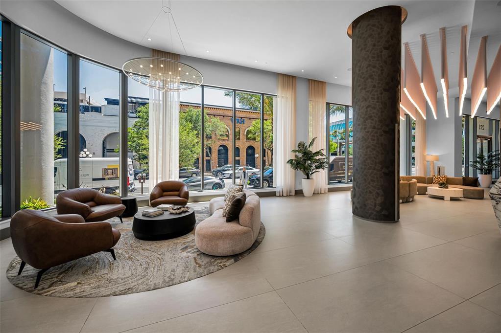 A modern lobby features floor-to-ceiling windows, a large circular rug, and contemporary seating areas — 275 1ST AVENUE S UNIT 3503, ST PETERSBURG, FL
