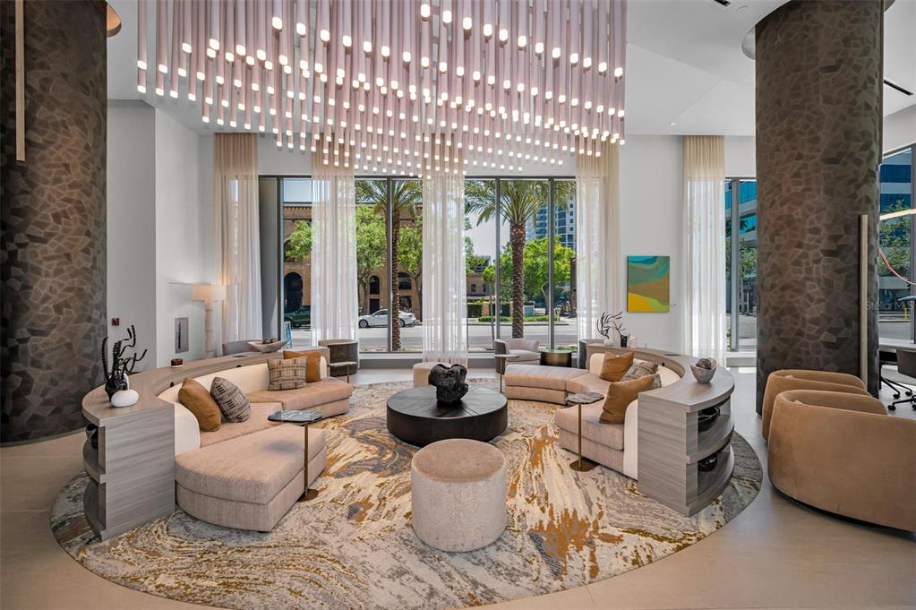 A modern lobby features a large circular rug, curved seating, and a prominent hanging light fixture — 275 1ST AVENUE S UNIT 3503, ST PETERSBURG, FL