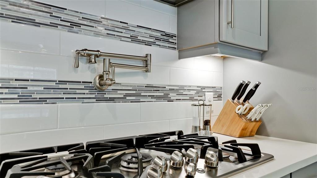 A kitchen stove features a wall-mounted pot filler faucet and a tiled backsplash — 5738 HYDRANGEA CIRCLE, SARASOTA, FL