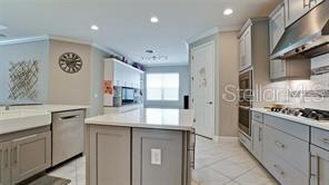 A kitchen features a central island, grey cabinetry, stainless steel appliances, and light-colored tile flooring — 5738 HYDRANGEA CIRCLE, SARASOTA, FL
