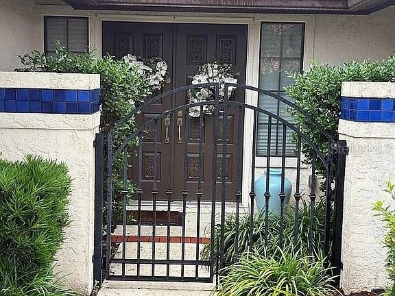 A black metal gate stands before a brown double front door with white floral wreaths — 4018 CORRIENTES COURT E, JACKSONVILLE, FL