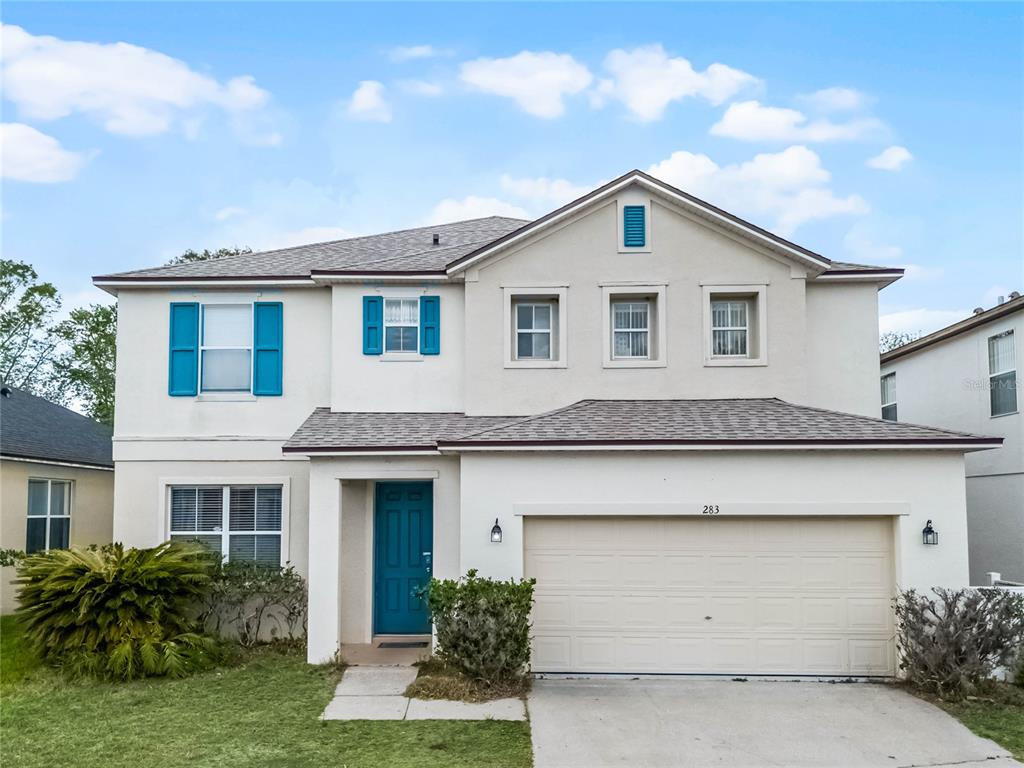 A two-story house with a beige stucco exterior, blue shutters, and a two-car garage — 283 WILLOW VIEW DRIVE, DAVENPORT, FL