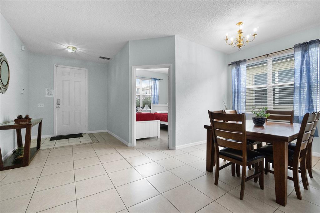 A dining area with a wooden table and chairs sits near an entryway and bedroom — 283 WILLOW VIEW DRIVE, DAVENPORT, FL