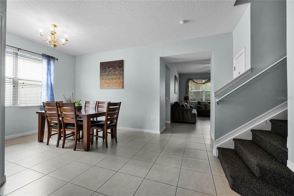 A dining area with tile floors, a wooden table, and stairs leading to an upper level — 283 WILLOW VIEW DRIVE, DAVENPORT, FL