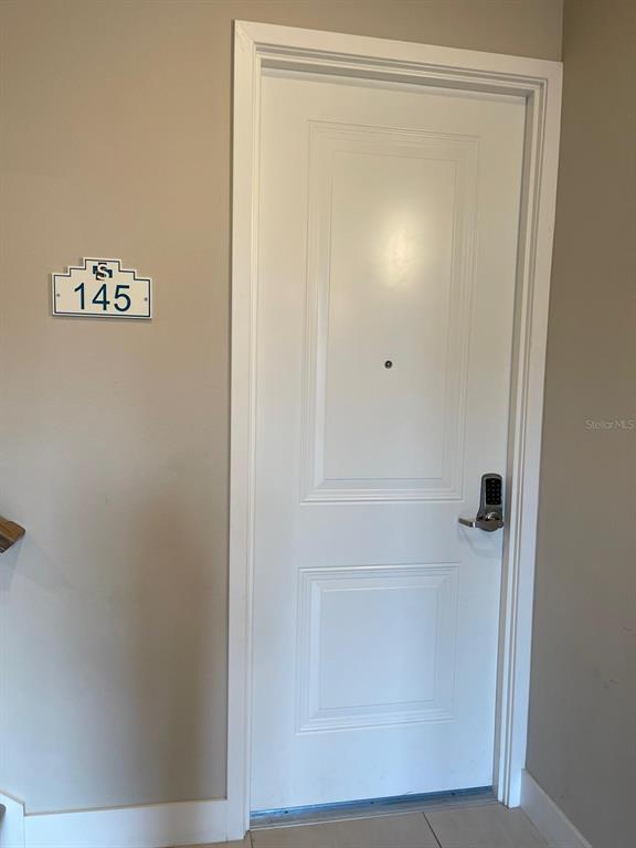 A white door with a digital keypad lock and a room number sign labeled 145 — 7770 SANDY RIDGE DRIVE UNIT 145, REUNION, FL
