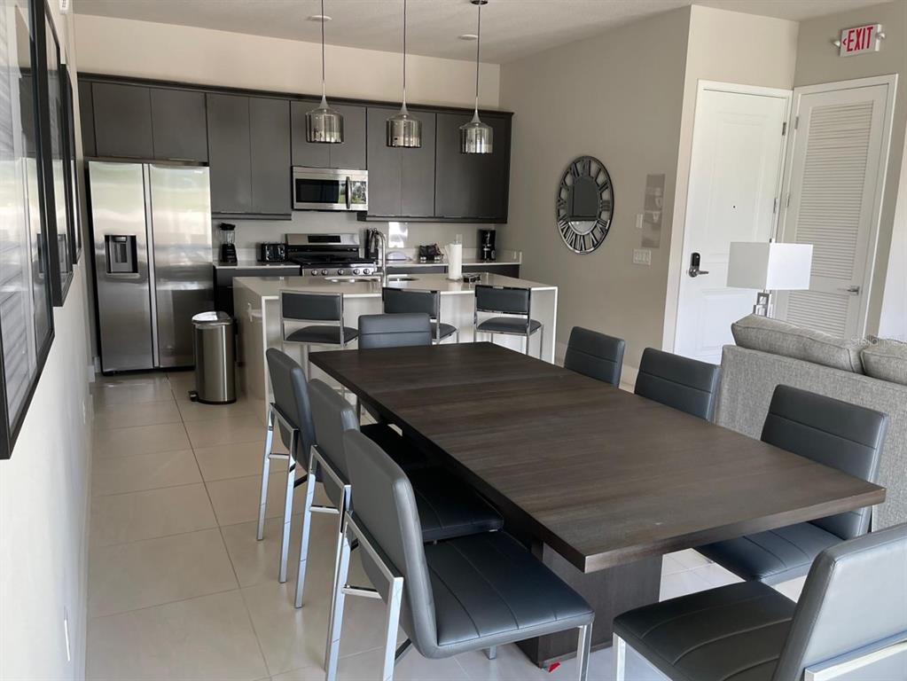 A modern kitchen and dining area features dark cabinetry, stainless steel appliances, and a large table — 7770 SANDY RIDGE DRIVE UNIT 145, REUNION, FL