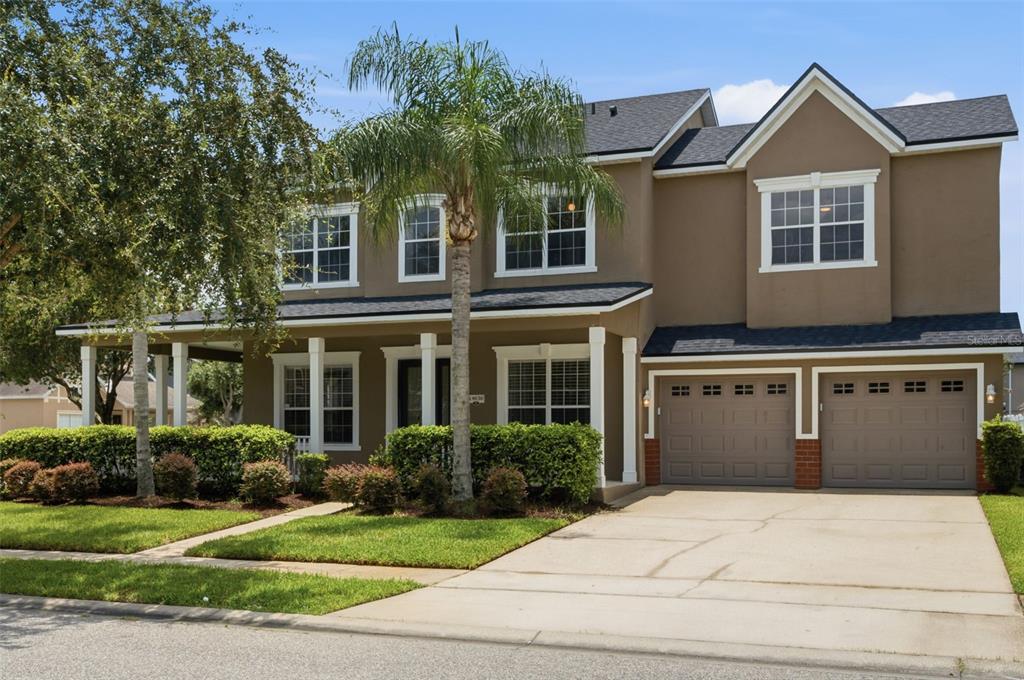 The exterior of a house features a dark front door, white columns, and landscaped bushes — 14636 MAILER BOULEVARD, ORLANDO, FL
