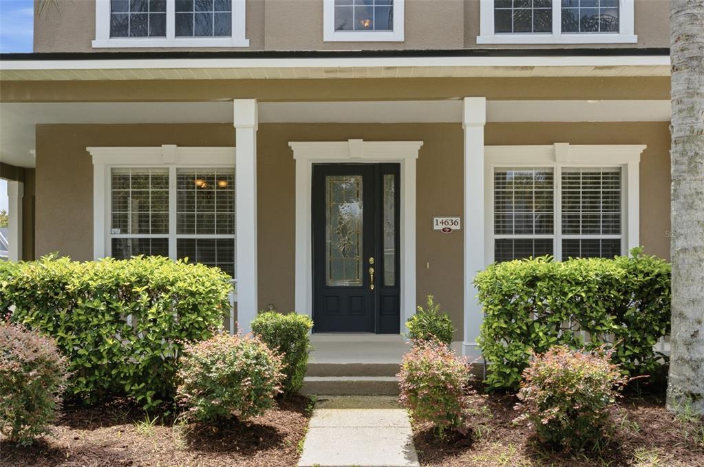 A covered front porch features a dark door with glass panels and a nearby window — 14636 MAILER BOULEVARD, ORLANDO, FL
