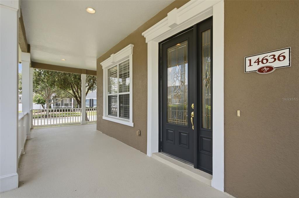 A covered exterior porch features tan stucco walls, white trim, and dark-framed glass doors — 14636 MAILER BOULEVARD, ORLANDO, FL