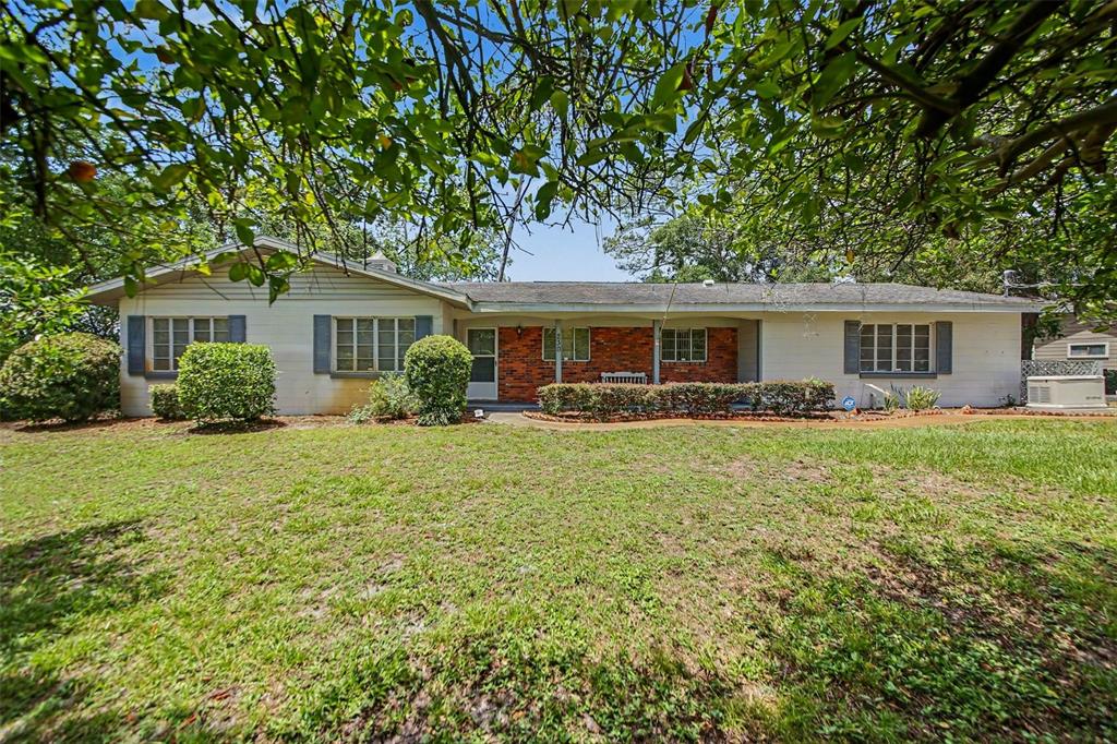 A single-story house with a brick and light-colored siding exterior sits behind a grassy lawn — 230 S CRYSTAL DRIVE, SANFORD, FL