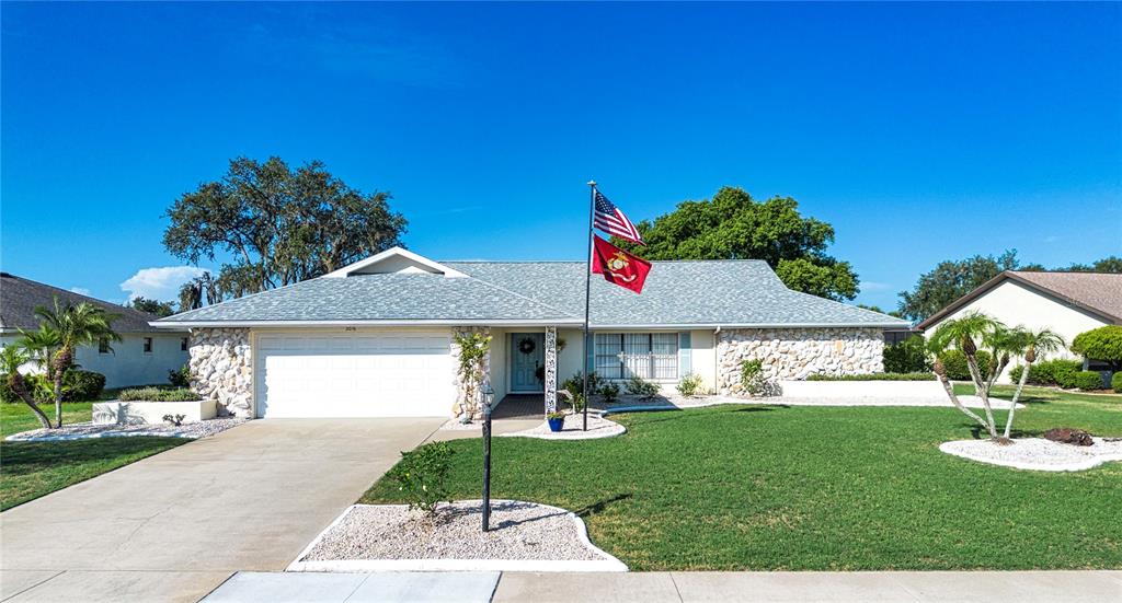 A single-story house with a white garage, stone facade, and a flag pole in front — 2016 E VIEW DRIVE, SUN CITY CENTER, FL