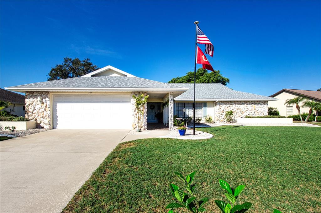 A single-story house with a stone facade, a two-car garage, and a flagpole — 2016 E VIEW DRIVE, SUN CITY CENTER, FL