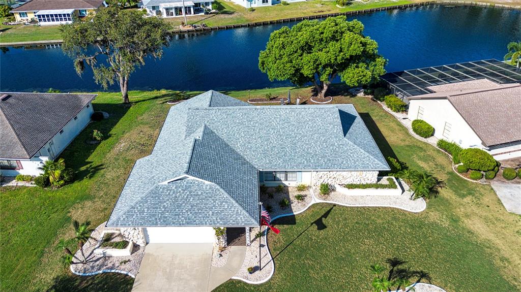 An aerial view of a single-story house with a gray shingled roof near a canal — 2016 E VIEW DRIVE, SUN CITY CENTER, FL