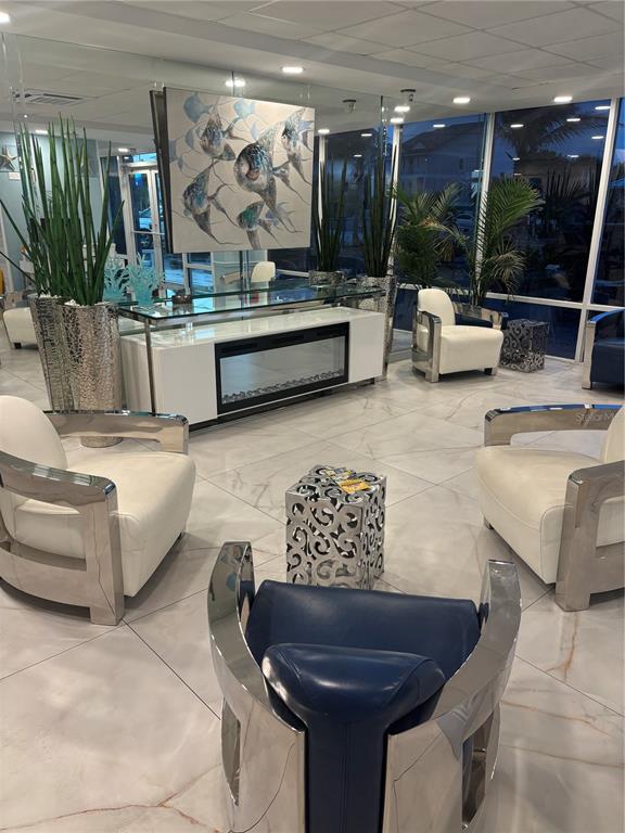 A modern lobby features white armchairs, a blue chair, a fireplace console, and fish artwork — 9980 GULF BOULEVARD UNIT 317, ST PETERSBURG, FL