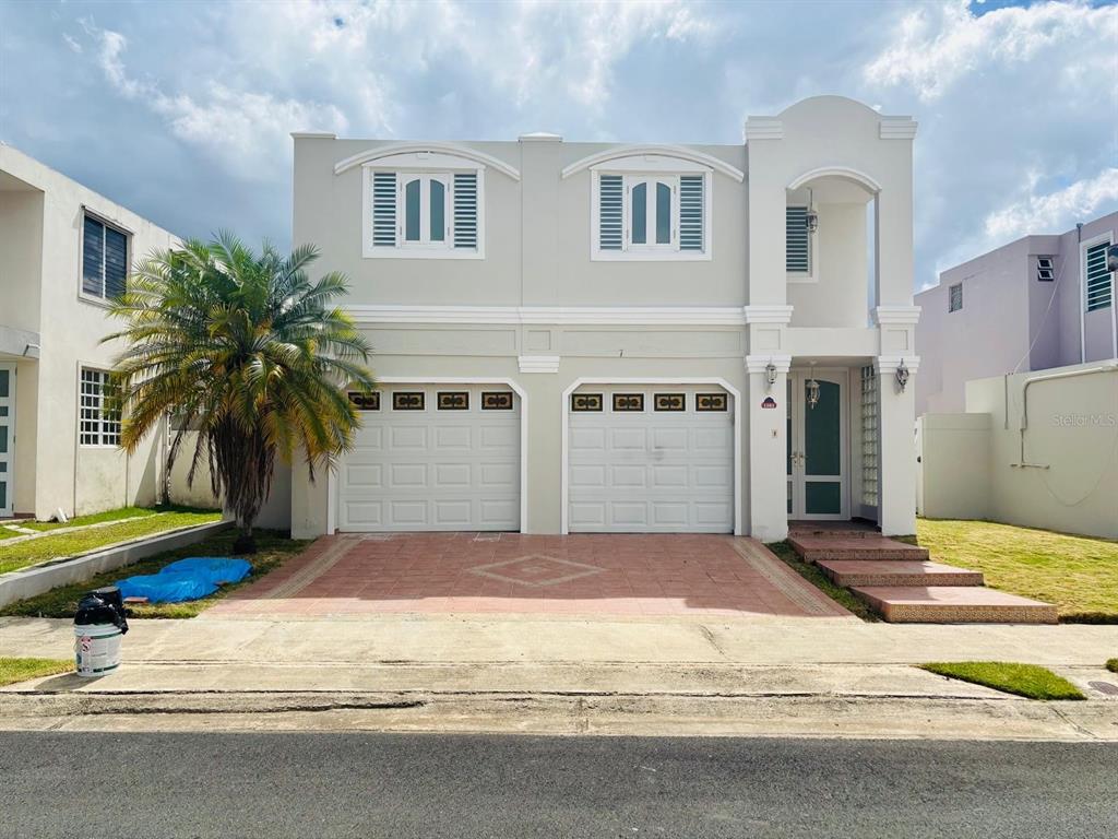 A two-story house with a light-colored facade, two garage doors, and a palm tree — Plaza de las Fuentes PLAZA DE LAS FUENTES, TOA ALTA, PR