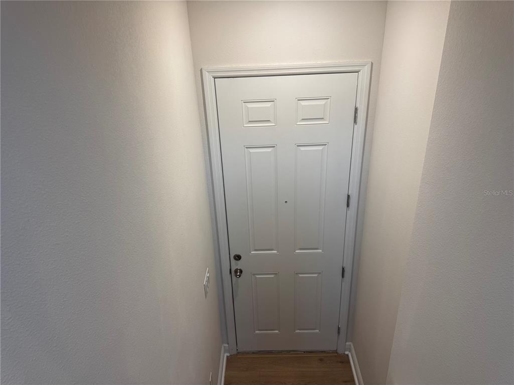 A white six-panel door is centered between two plain walls above a wood floor — 5364 SPADERDOCK LANE Apt-Above-Garage, APOPKA, FL