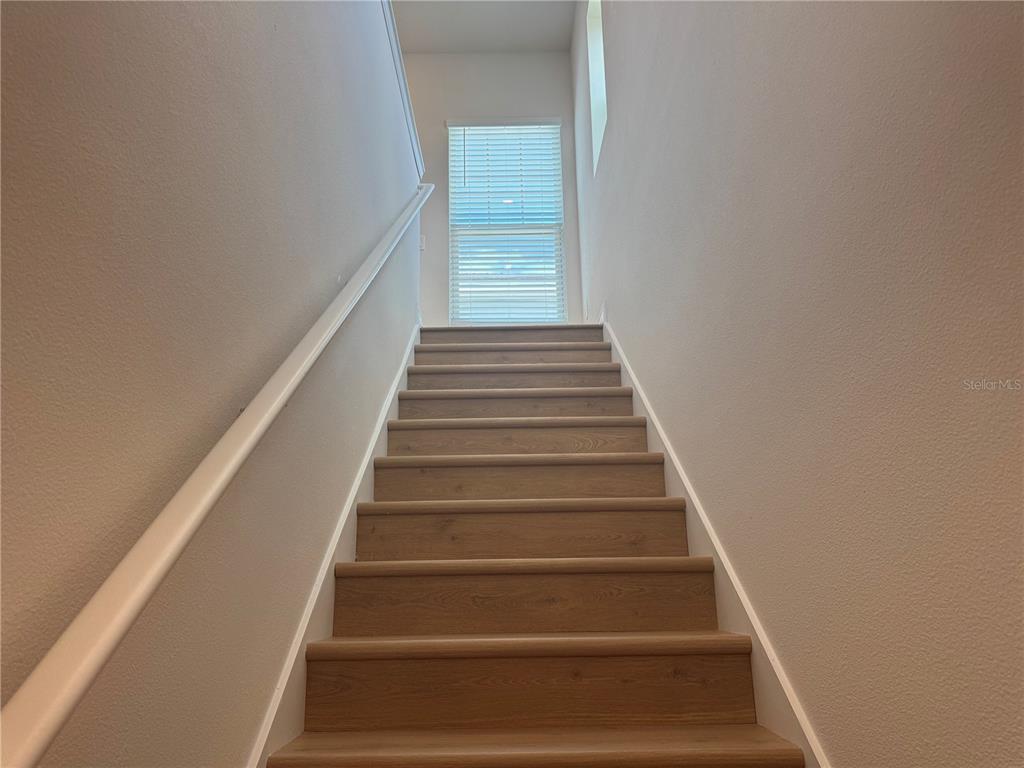 A wooden staircase with a white handrail leads up to a window with blinds — 5364 SPADERDOCK LANE Apt-Above-Garage, APOPKA, FL