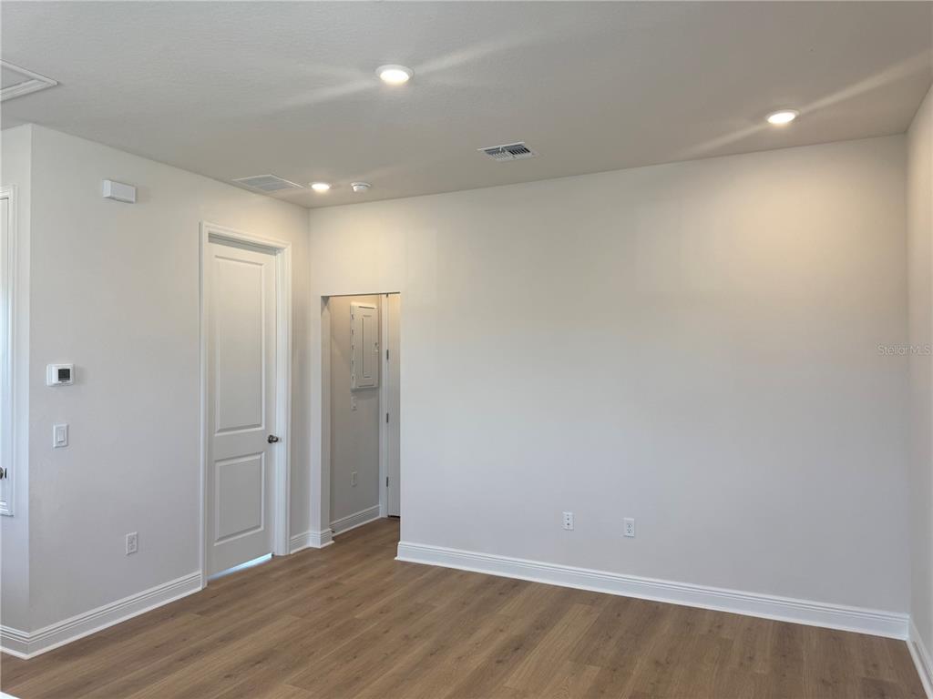 An empty room features light wood-look flooring, white walls, recessed lighting, and a doorway — 5364 SPADERDOCK LANE Apt-Above-Garage, APOPKA, FL