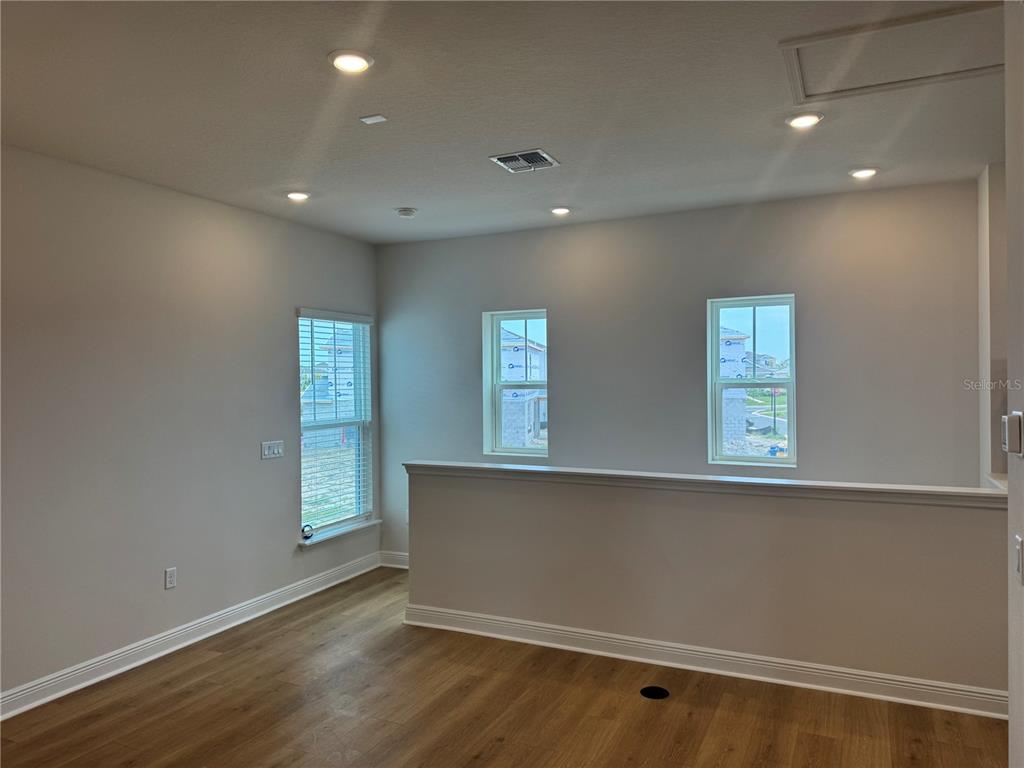 An empty room features light wood-look flooring, recessed lighting, and a half-wall overlooking another area — 5364 SPADERDOCK LANE Apt-Above-Garage, APOPKA, FL
