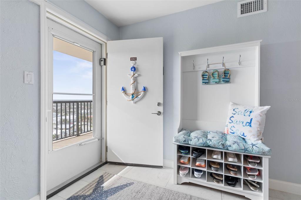 An entryway features a white door with an anchor decoration, a shoe rack, and a balcony — 89 S ATLANTIC AVENUE UNIT 1002, ORMOND BEACH, FL