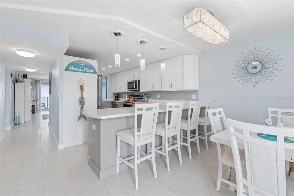 A kitchen with white cabinets, a gray island, and a dining area with white chairs — 89 S ATLANTIC AVENUE UNIT 1002, ORMOND BEACH, FL