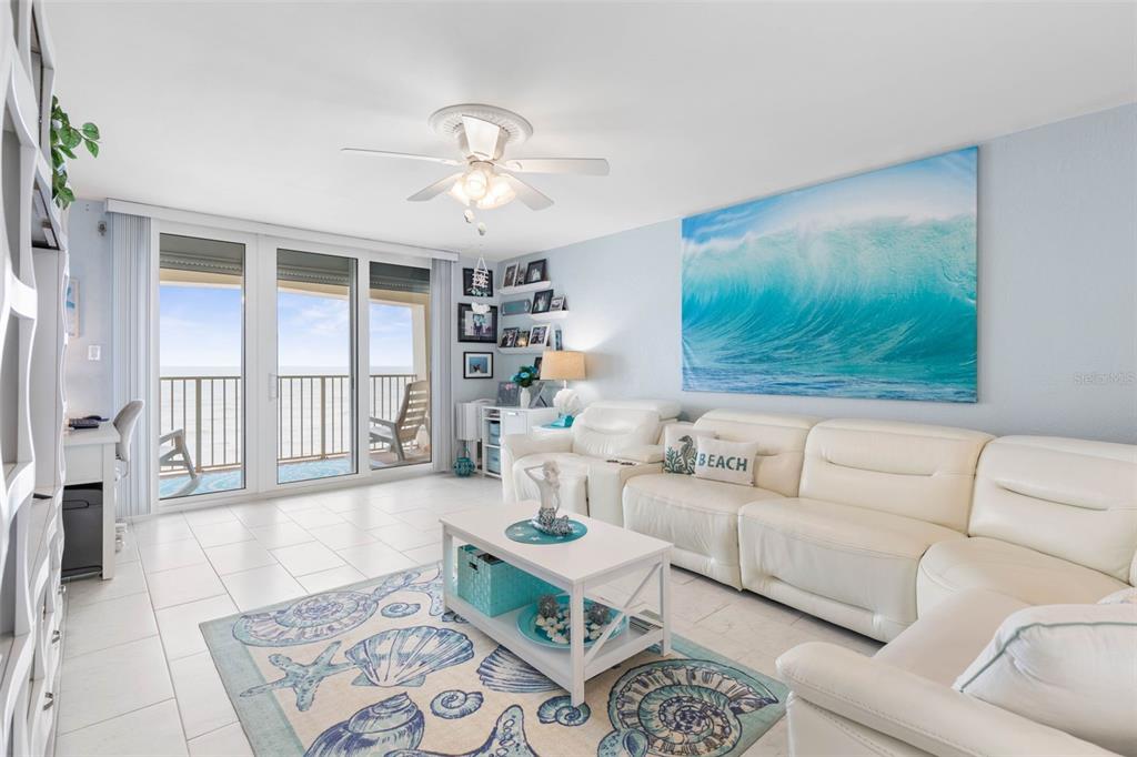 A living room features white leather furniture, a shell-patterned rug, and a large ocean wave print — 89 S ATLANTIC AVENUE UNIT 1002, ORMOND BEACH, FL