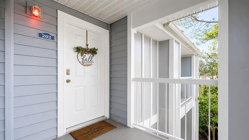 A living room with hardwood floors and a rug opens to a kitchen with tile — 2548 GRASSY POINT DRIVE UNIT 202, LAKE MARY, FL