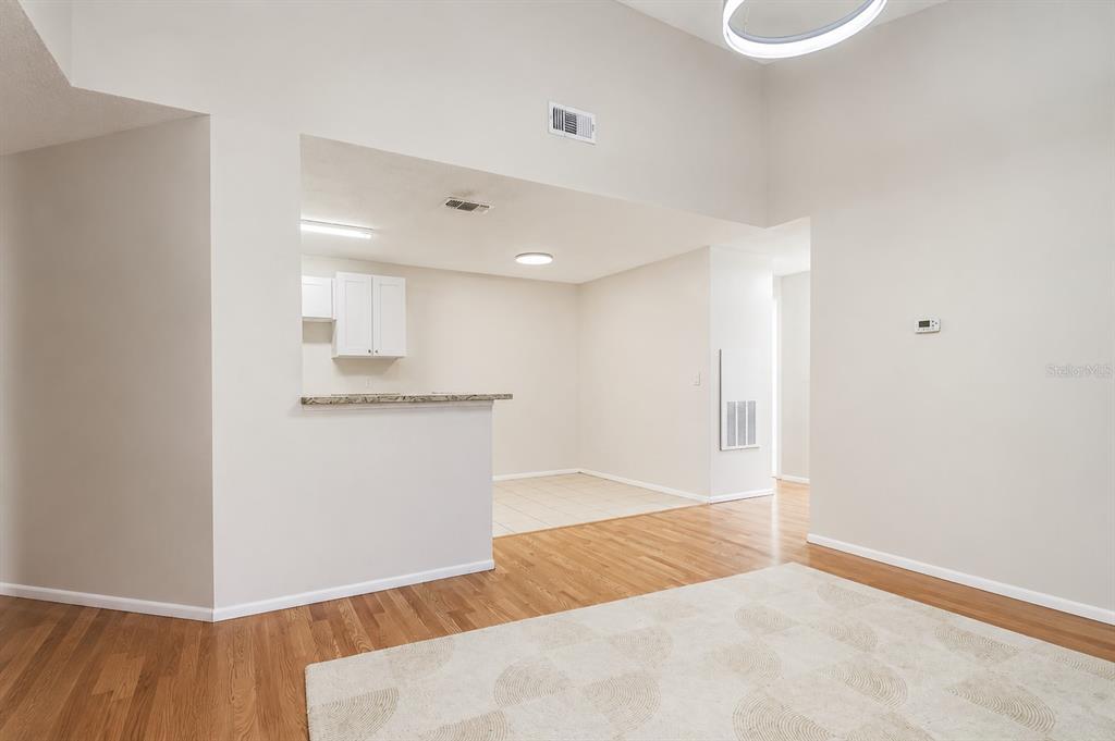 A room with light wood floors, a checkered rug, and black curtains over sliding doors — 2548 GRASSY POINT DRIVE UNIT 202, LAKE MARY, FL