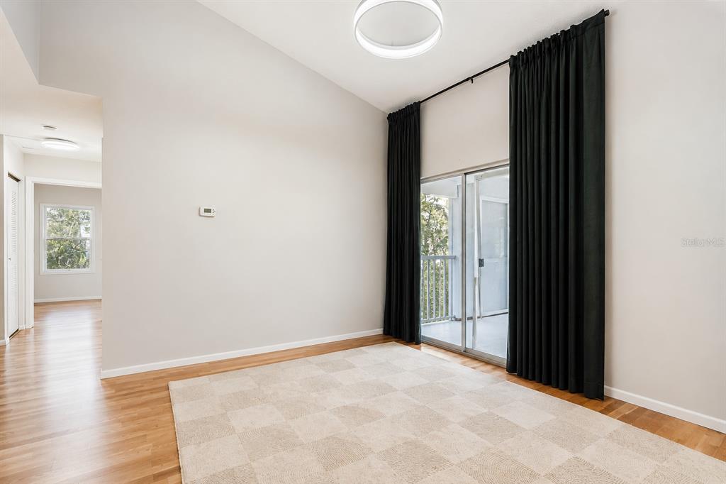 A living room features light wood flooring, a wall-mounted television, and a sliding glass door — 2548 GRASSY POINT DRIVE UNIT 202, LAKE MARY, FL