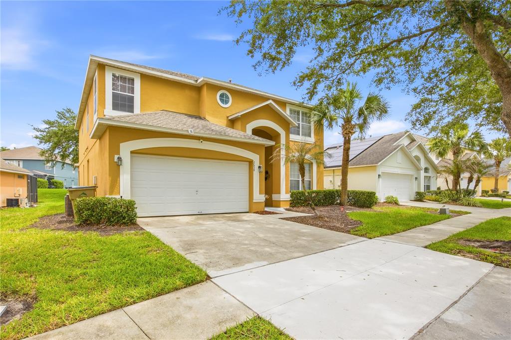 A two-story yellow house with a two-car garage and a concrete driveway — 2658 EMERALD ISLAND BOULEVARD, KISSIMMEE, FL