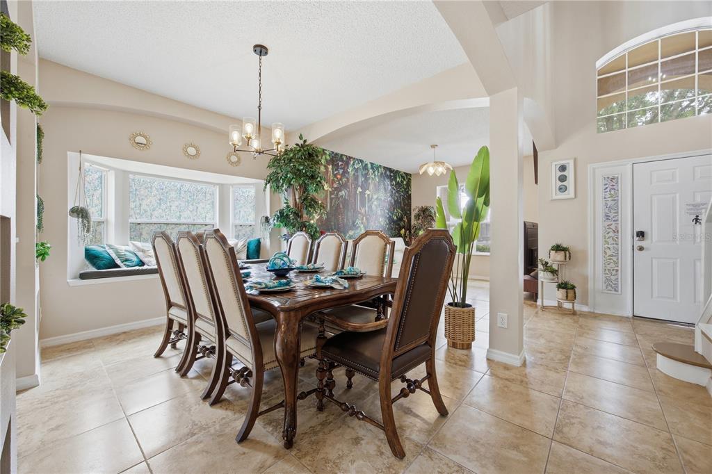 A dining room features a wooden table with upholstered chairs, tiled floors, and a mural wall — 2658 EMERALD ISLAND BOULEVARD, KISSIMMEE, FL