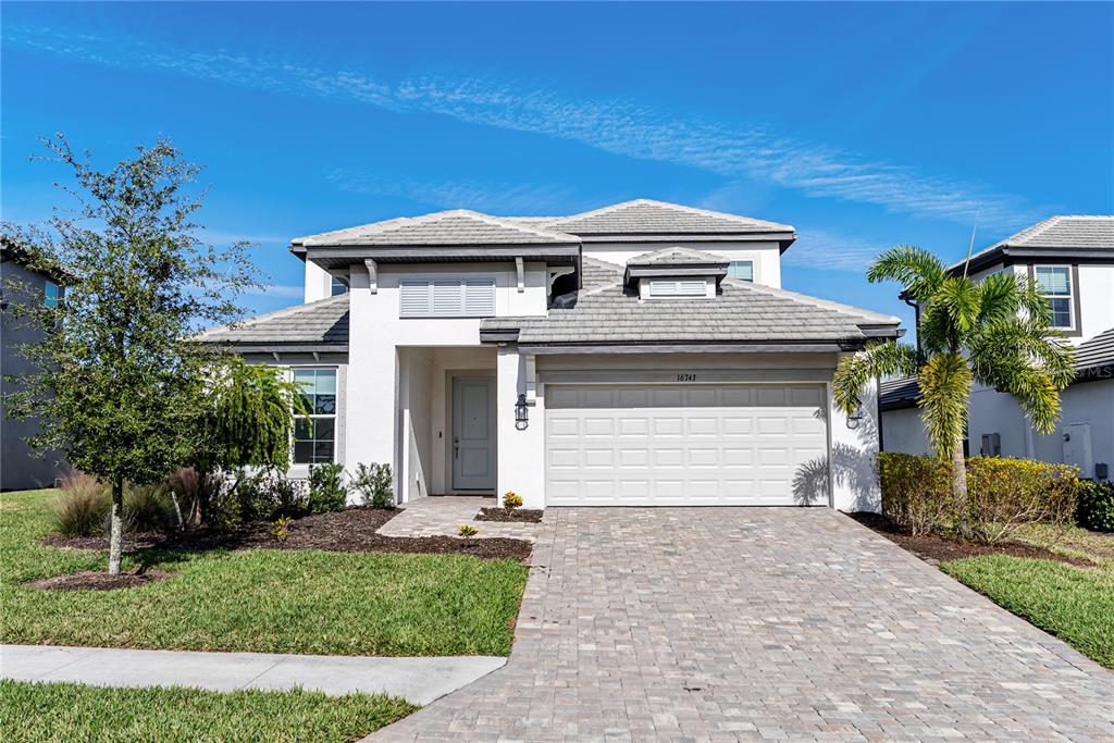 A two-story house with a white stucco exterior, a tiled roof, and a paved driveway — 16743 SERAPHIC TRAIL, BRADENTON, FL