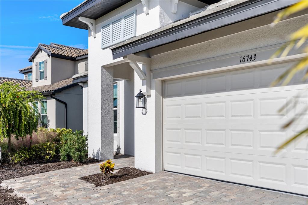 A white house exterior features a paved driveway, a garage door, and a covered entryway — 16743 SERAPHIC TRAIL, BRADENTON, FL