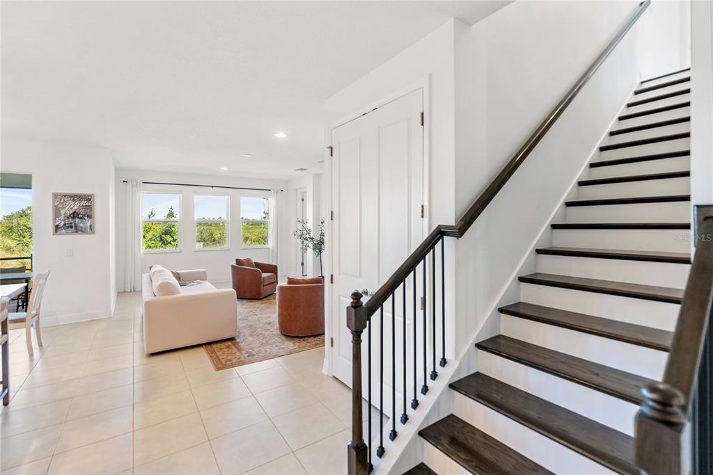 A bright living room features tile floors, a staircase with dark treads, and large windows — 16743 SERAPHIC TRAIL, BRADENTON, FL