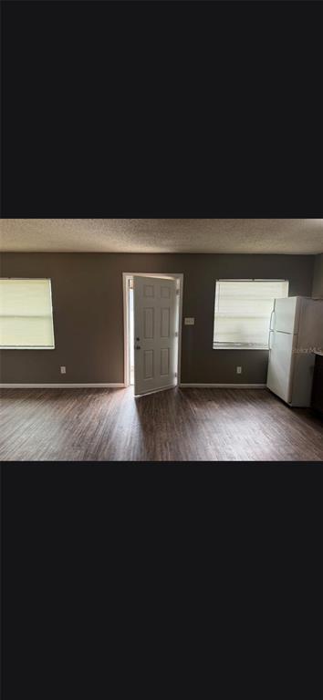 A room with dark wood-look flooring, gray walls, two windows, and an open exterior door — 3413 E 12TH AVENUE UNIT A, TAMPA, FL