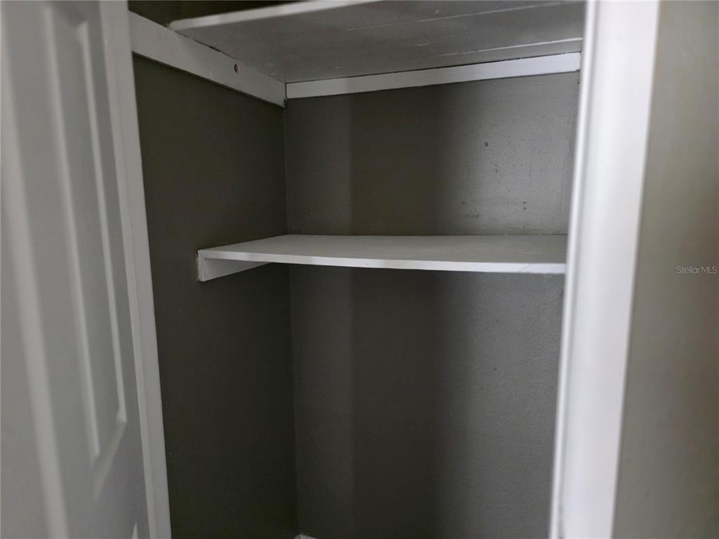 A small closet with dark gray walls and two white wooden shelves — 3413 E 12TH AVENUE UNIT A, TAMPA, FL
